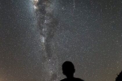 silhouette of man standing under starry night